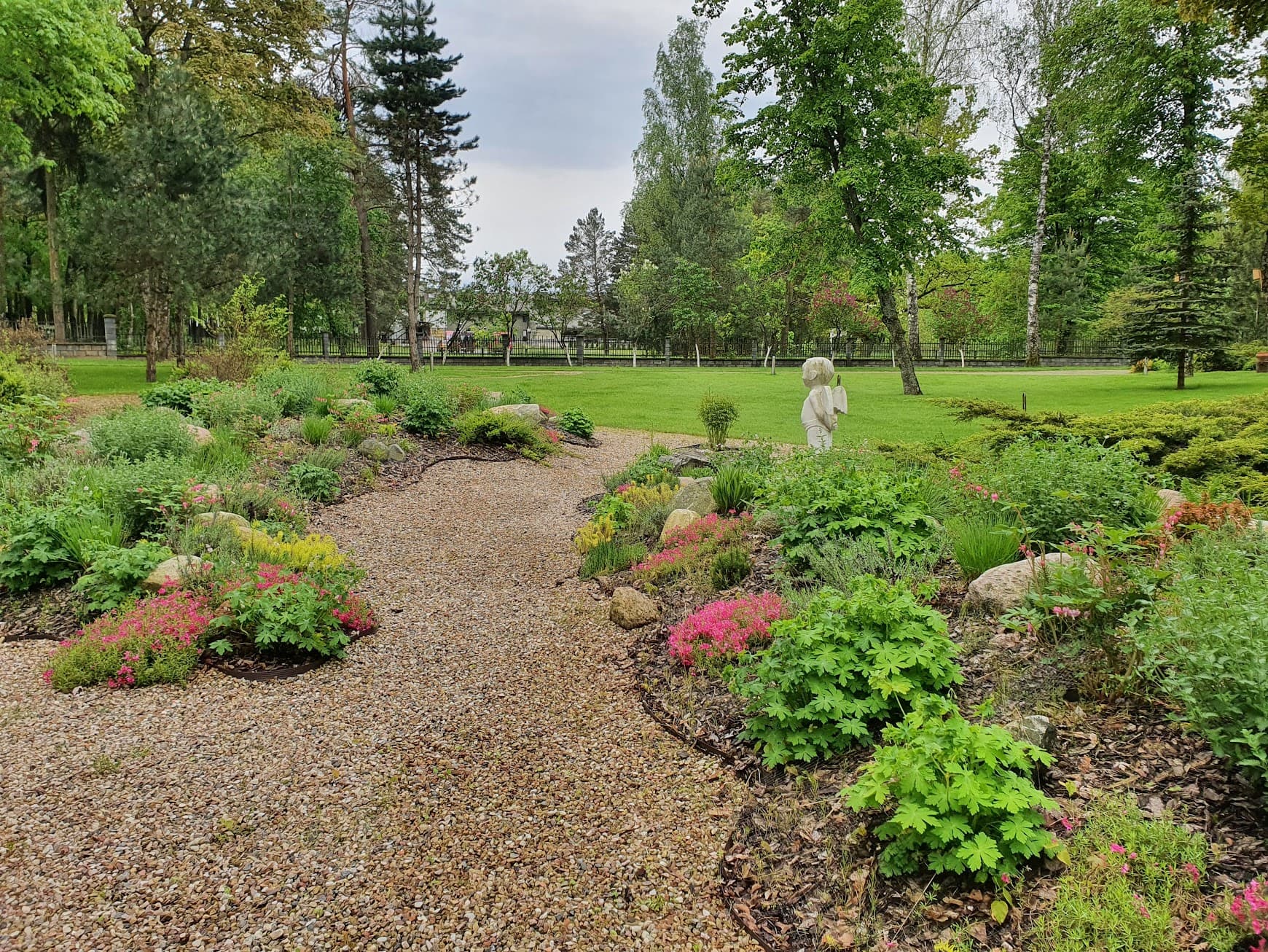 Park flowerbed with gravel path and statue