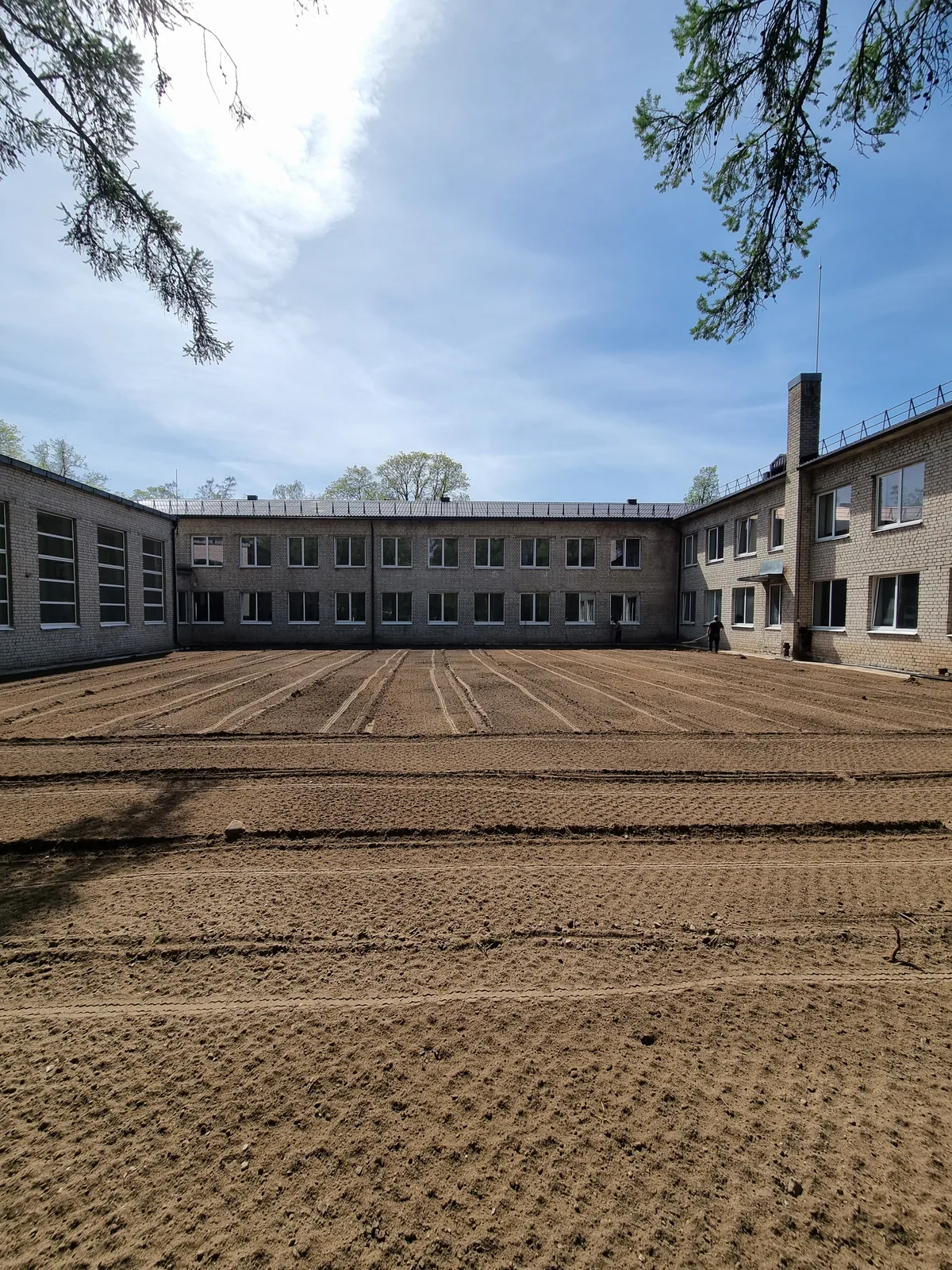 Išlygintas gruntas Bukiškio progimnazijos kieme prieš vejos sėją