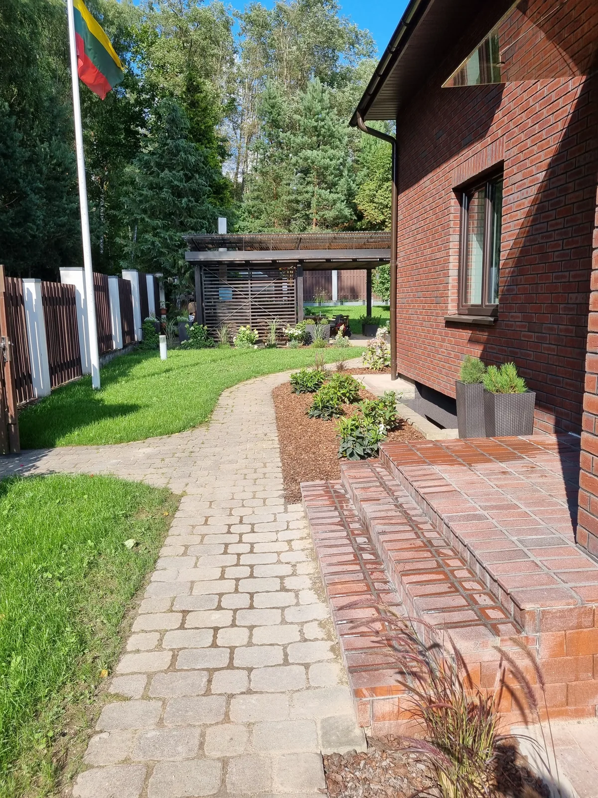 Sutvarkytas takas ir želdiniai palei namą Lazdynėliuose
